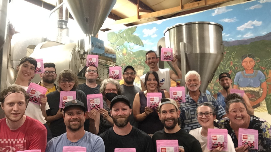 Staff photo holding pink coffee bags inside of a Ukrainian flag