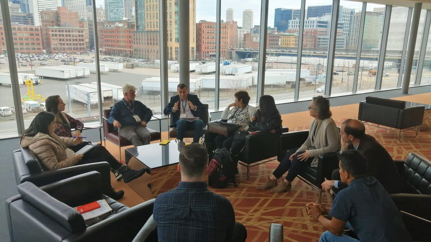 Dean with several farmer sitting in a circle having a discussion. Cityscape in the background.