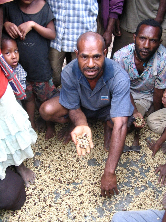 A man holding up a handful of green beans to the camera