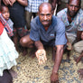 A man holding up a handful of green beans to the camera