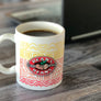 White ceramic coffee mug with colorful patterns and Dean's Beans logo