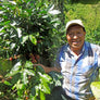 A smiling Guatemalan farmer showing off some coffee cherries