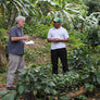 Dean talking with a farmer surrounded by small coffee plants