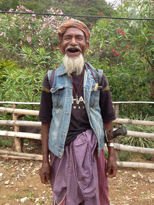 A farmer laughing, with a machete on his waist, in front of a forest