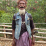 A farmer laughing, with a machete on his waist, in front of a forest