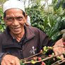 A smiling farmer showing off some of his coffee cherries