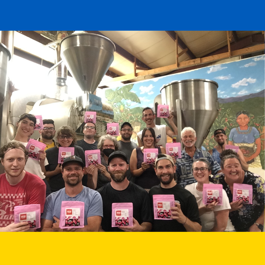Staff photo holding pink coffee bags inside of a Ukrainian flag