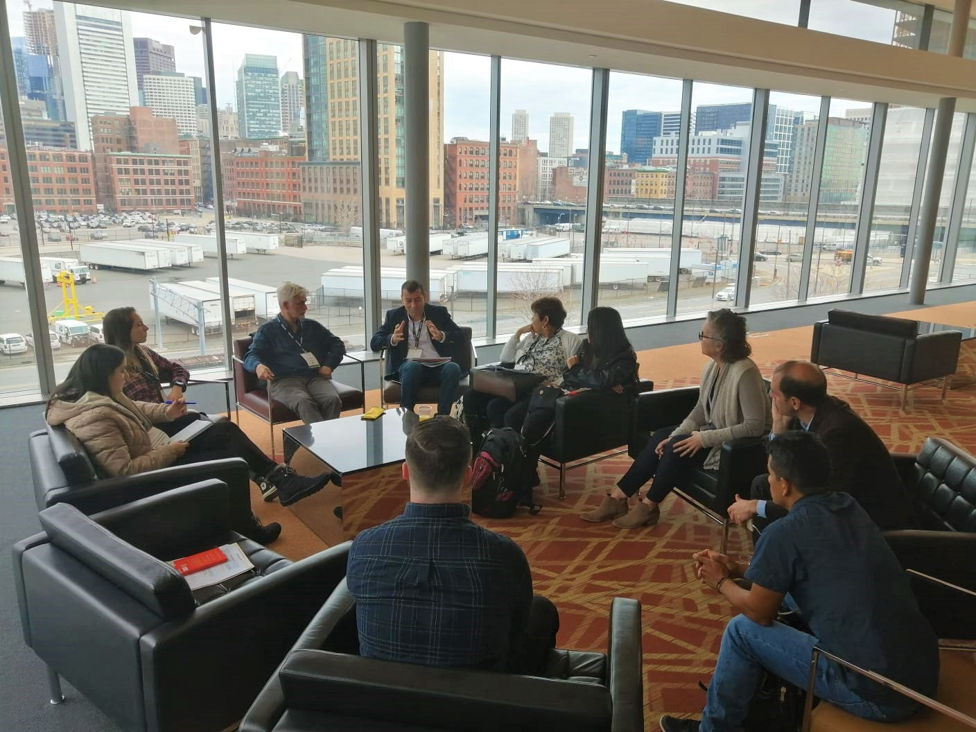 Dean with several farmer sitting in a circle having a discussion. Cityscape in the background.