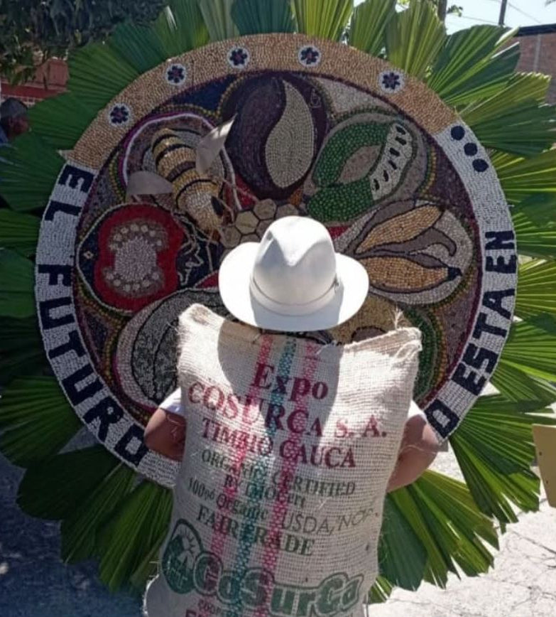 A farmer carrying a bag of coffee admires a decorative sign