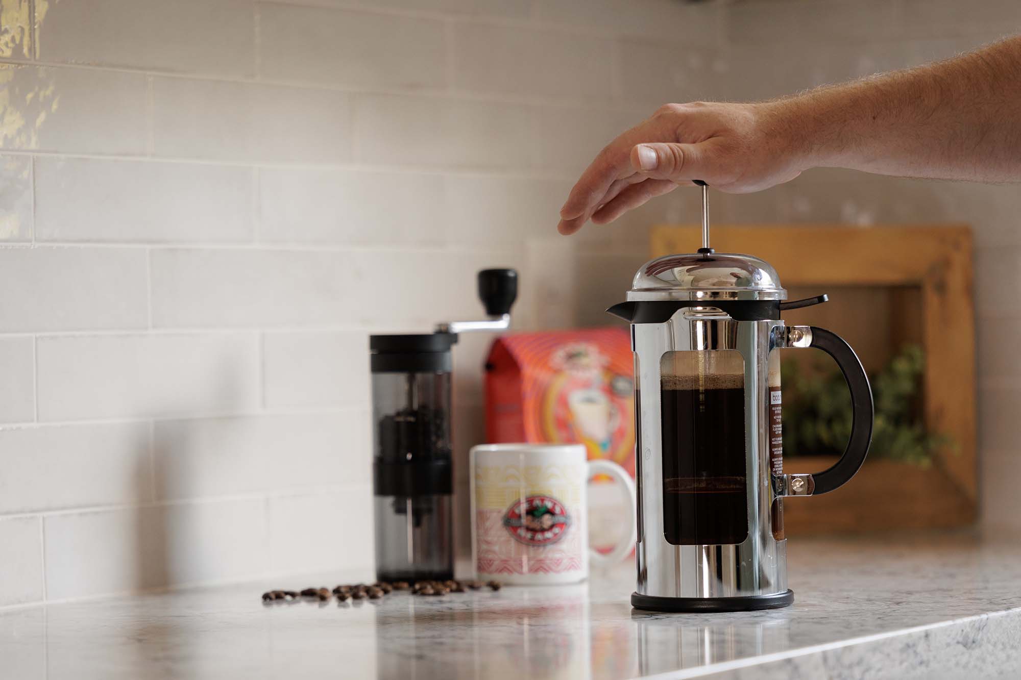 Person making coffee using a French press on a kitchen counter.