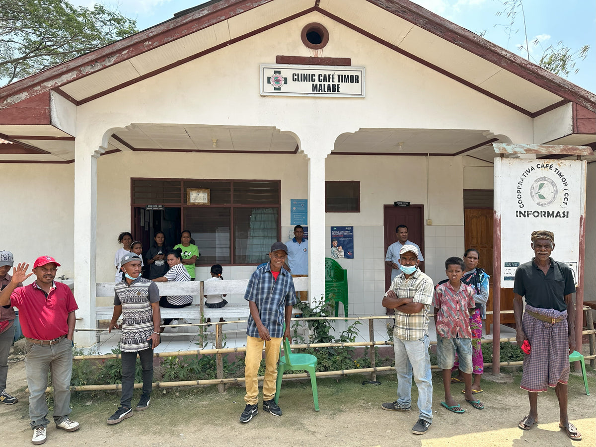 Group of people standing outside a clinic building with 'Clinic Cafe Unior Malabe' sign.