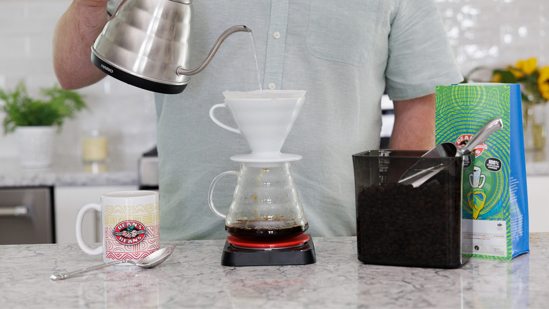 Person making coffee using a pour-over setup on a kitchen counter.