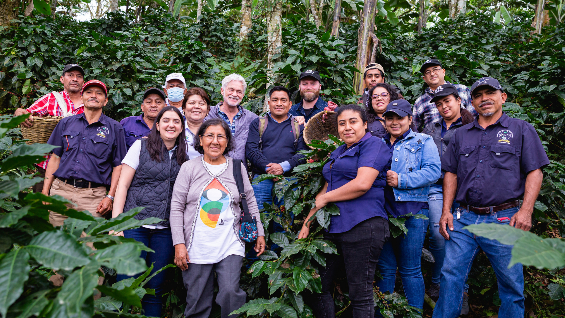 Our founder Dean and Head Roaster Brendan pose at a coffee farm with farmers from Colombia, Guatemala, Nicaragua, Peru, and Honduras