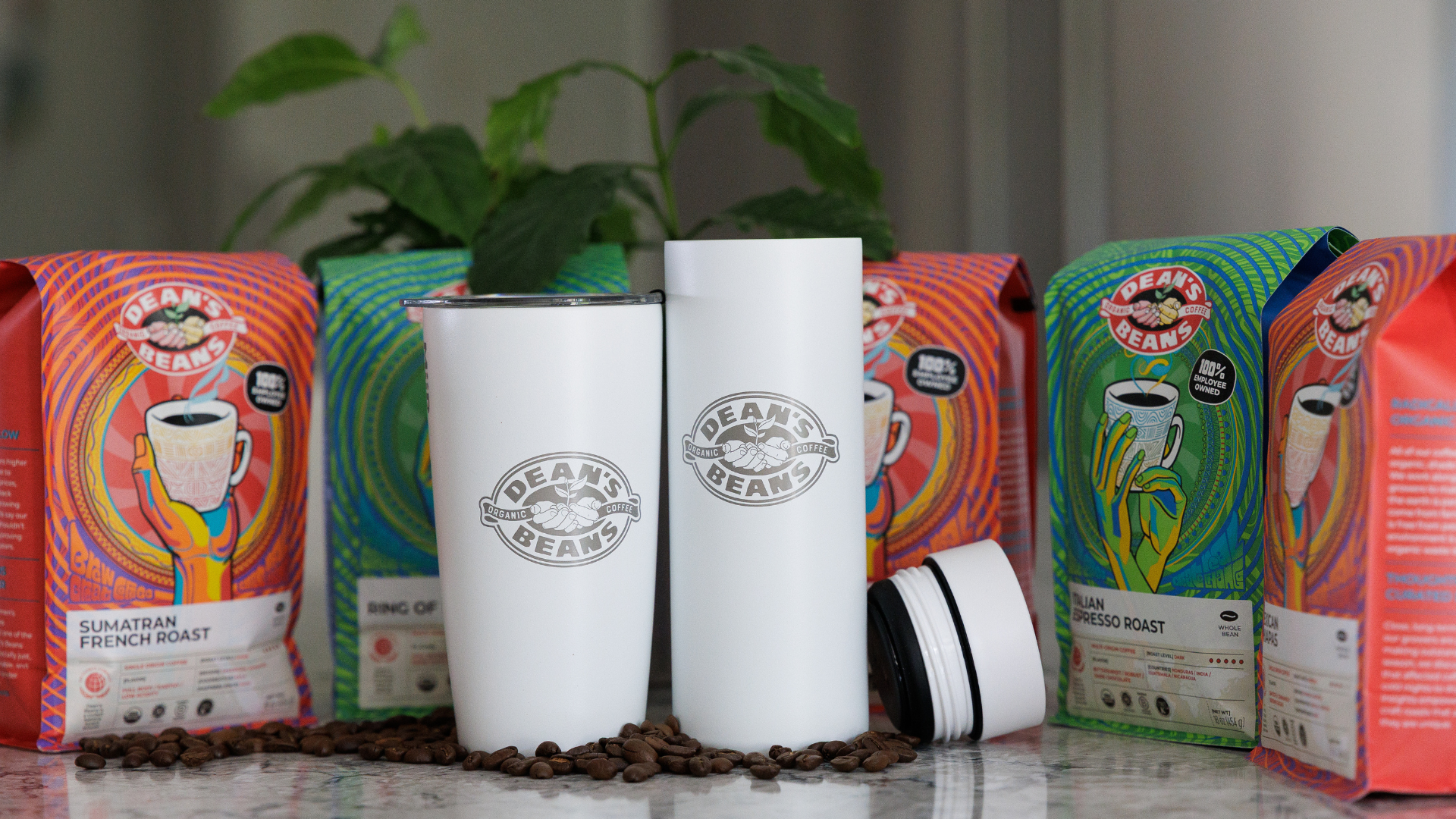 two dean's bean travel cups with bags of dean's beans coffee