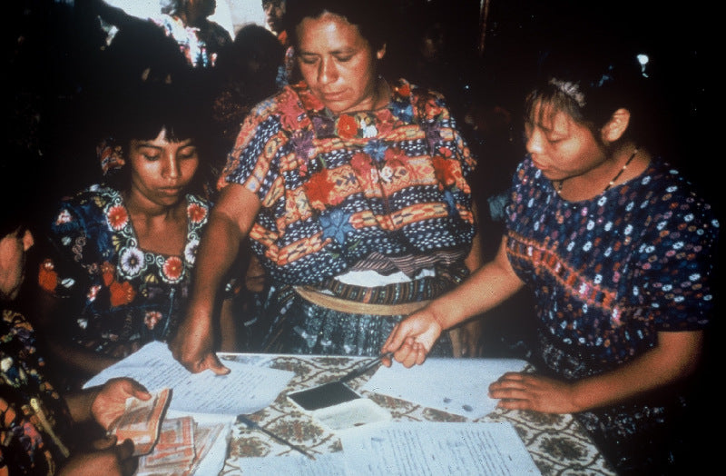 Guatemalan women stamping forms around a table