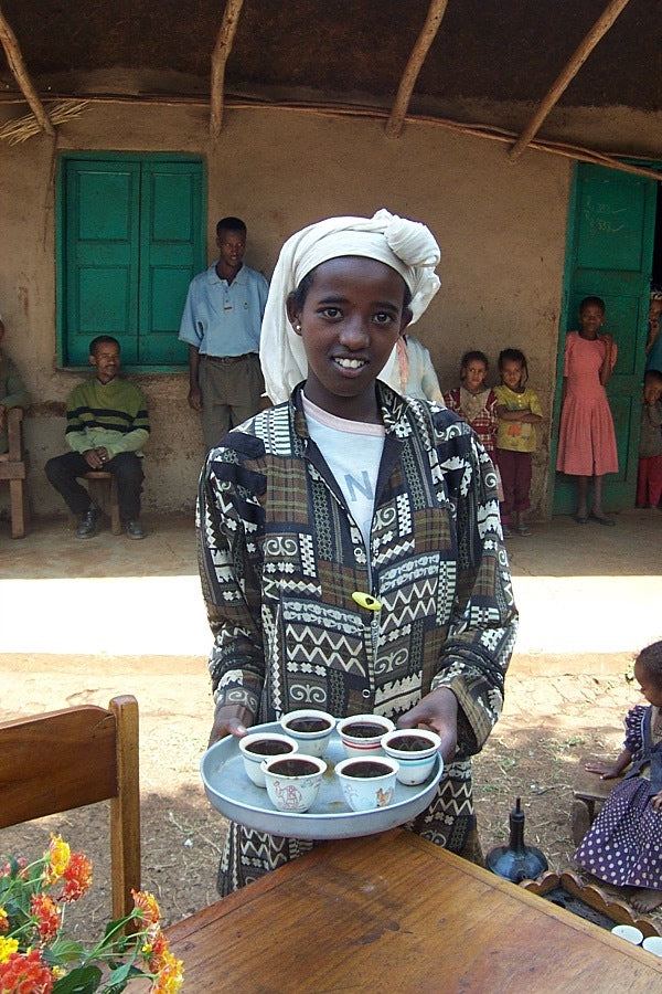 An Ethiopian girl carrying a small tray of coffee cups
