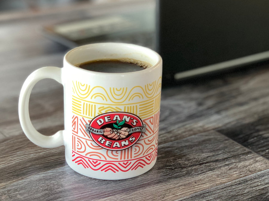 White ceramic coffee mug with colorful patterns and Dean's Beans logo