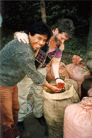 Young Dean and a farmer pulling handfuls of coffee cherries out of a bag