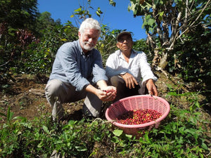 Dean and a farmer with a basket of coffee cherries