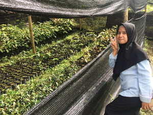 A woman holding up a peace sign next to a tree nursery